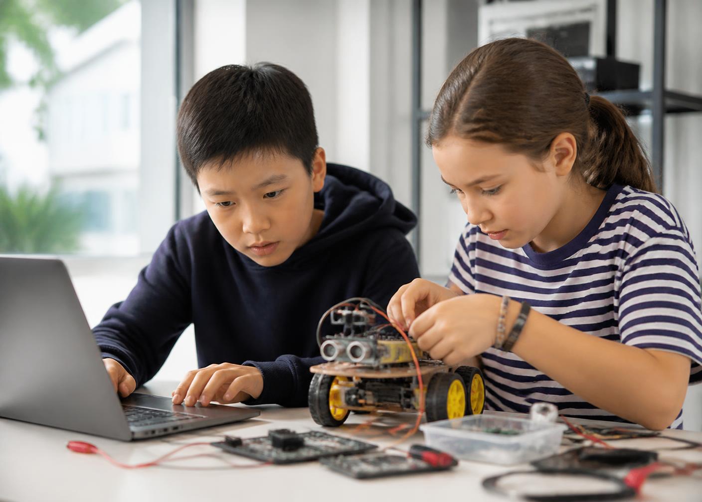 Two children building a robot together in the after school technology block